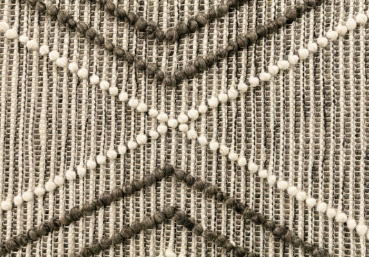 Charcoal and ivory wool rug with raised diamond texture and pom fringe