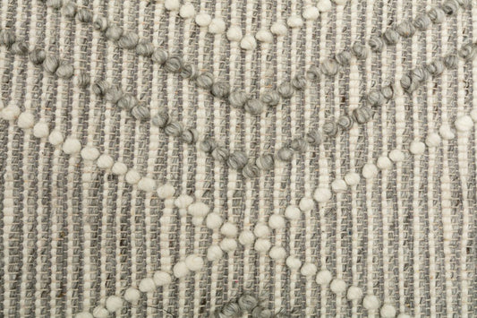 Silver gray wool rug detail with raised loops and small tassel-like accents