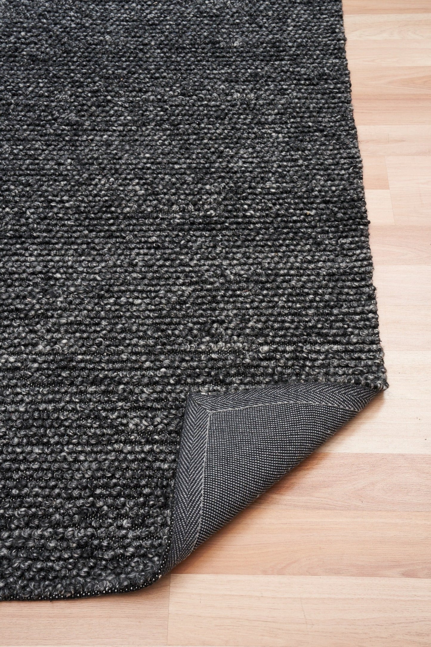 Charcoal textured area rug with stitched edge and looped fabric surface