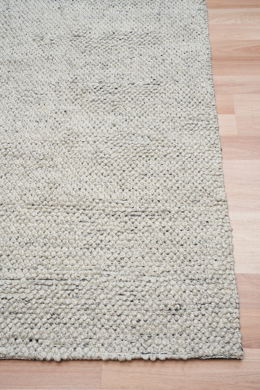 Grey textured area rug with dense loop texture and stitched edge
