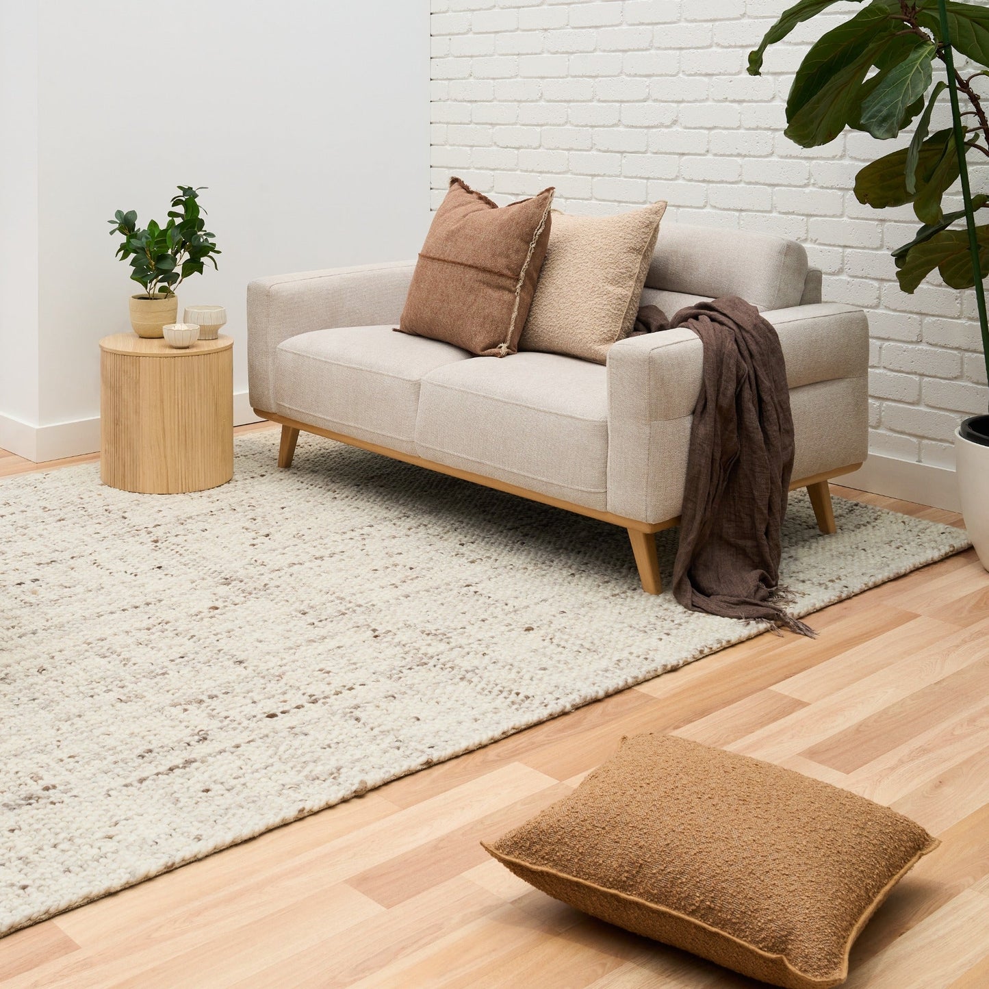Beige textured area rug in living space on light wood floor