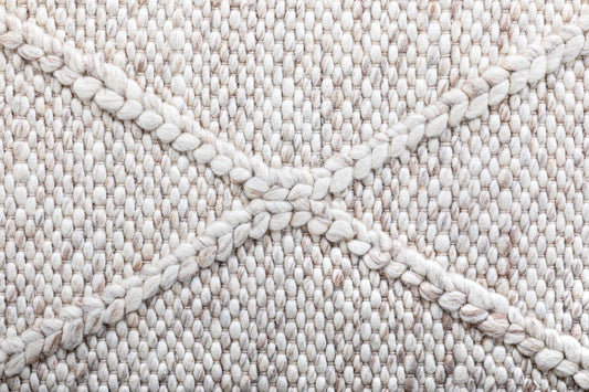 Beige wool rug texture close-up with looped braided yarn surface