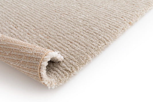 Beige rug corner with bound fringe detail and soft loop texture