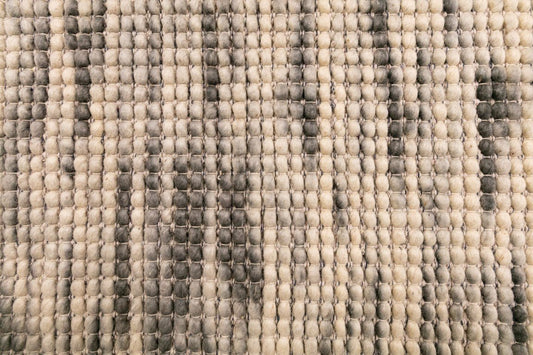 Wool rug surface with raised loop texture in ivory with dark gray grid lines