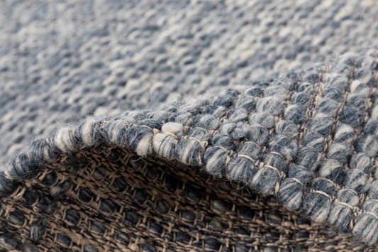 Wool rug border detail in blue-gray with textured edge and fringe