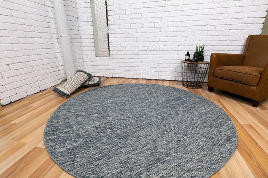 Round wool rug in dark gray on hardwood floor