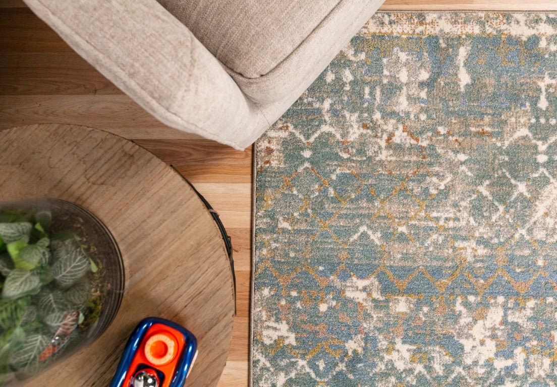 Large area rug with distressed geometric pattern in cream and blue; no fringe, stitched edge