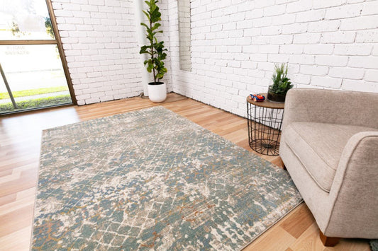 Large area rug laid flat with wide distressed motif in cream, blue, and muted tan