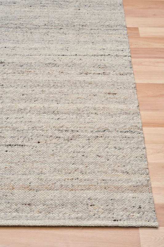 Smoke grey wool rug edge detail with speckled horizontal texture and binding