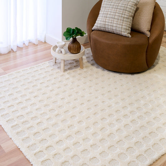 Cream rug with raised square-dot texture placed under a sofa and side table