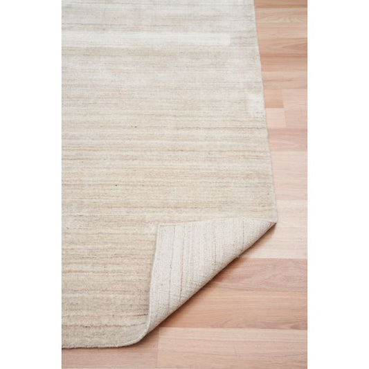 Beige wool rug with subtle horizontal stripes, corner shown with rolled edge