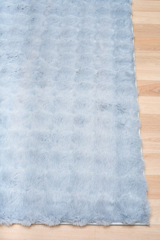 Light blue shag area rug with scalloped edge, corner shown
