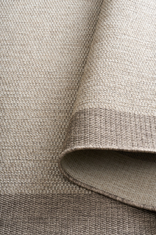 Taupe rug corner with textured flat weave and rolled edge