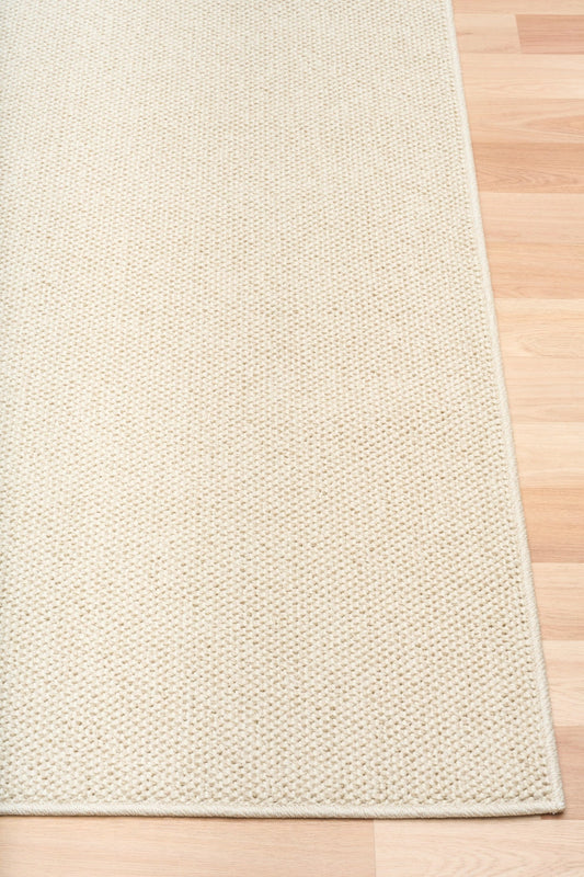 Cream woven area rug with squared border and tight, textured surface