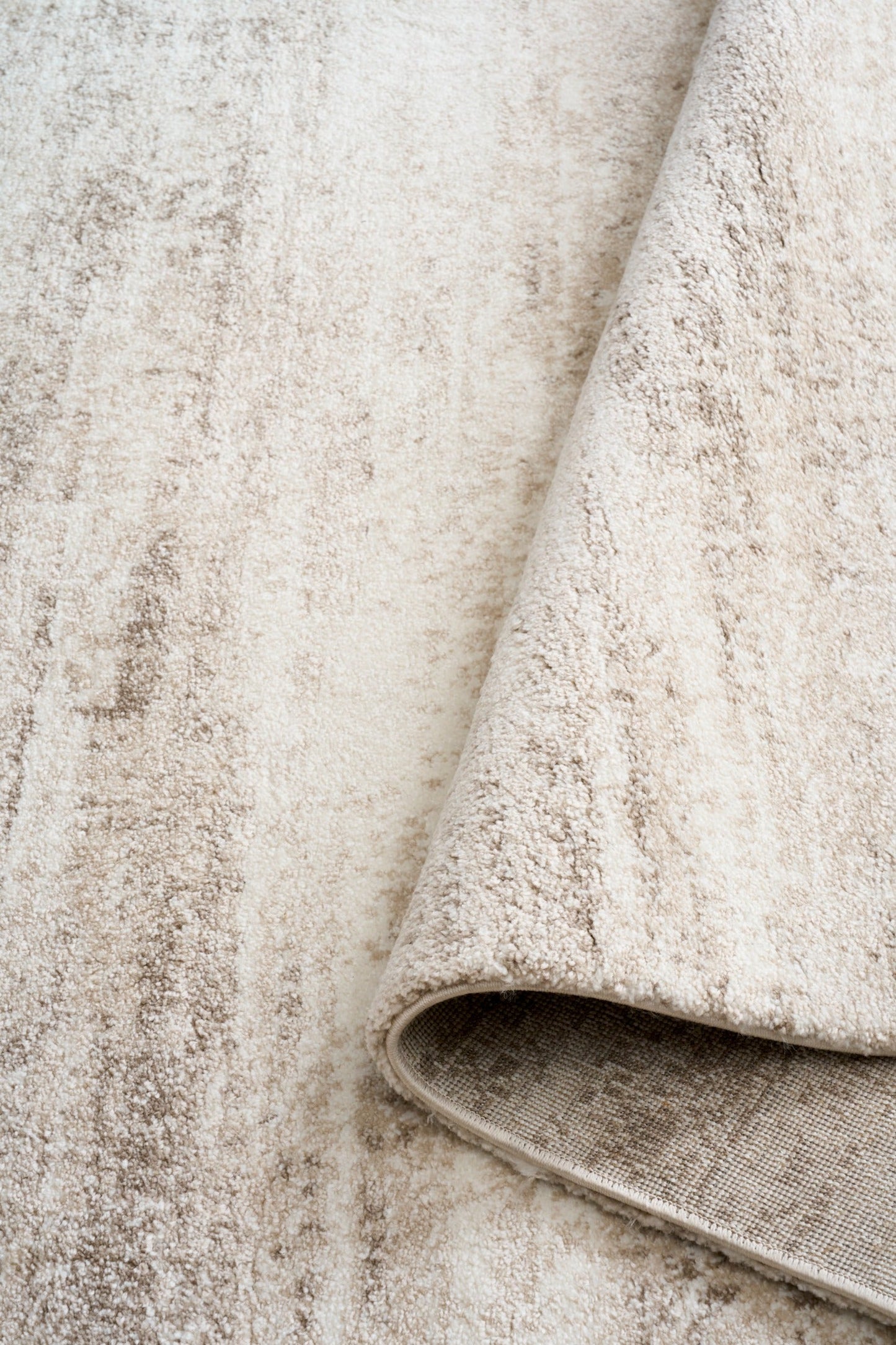 Bone cream area rug with short textured pile and distressed stripe pattern, rolled edge