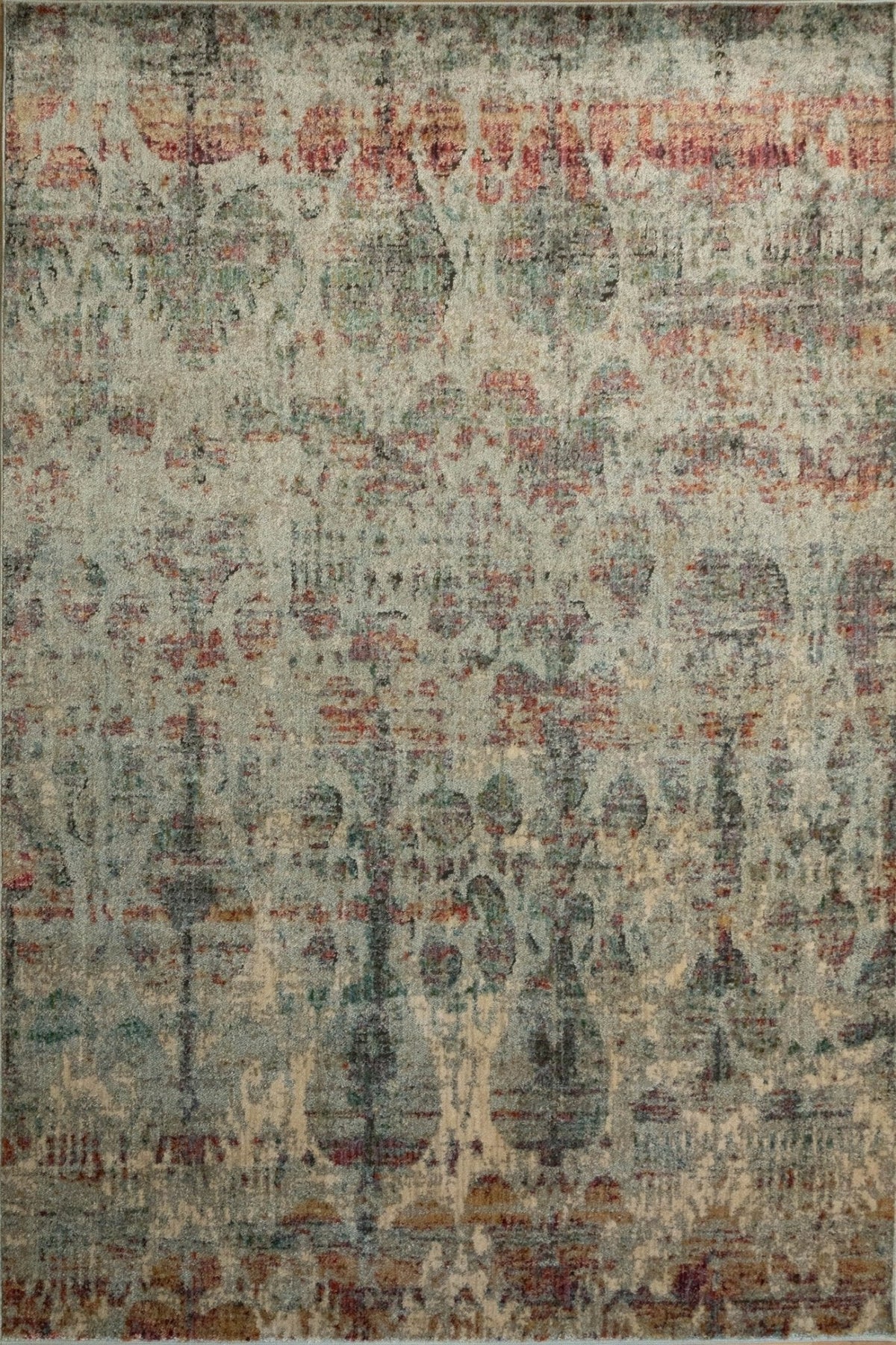 Close-up distressed rug with teal-gray field and beige rust motif pattern, textured pile