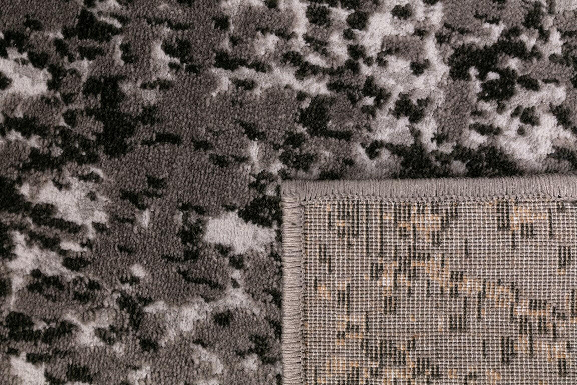 Rug corner with textured border and speckled gray, black, and white surface.