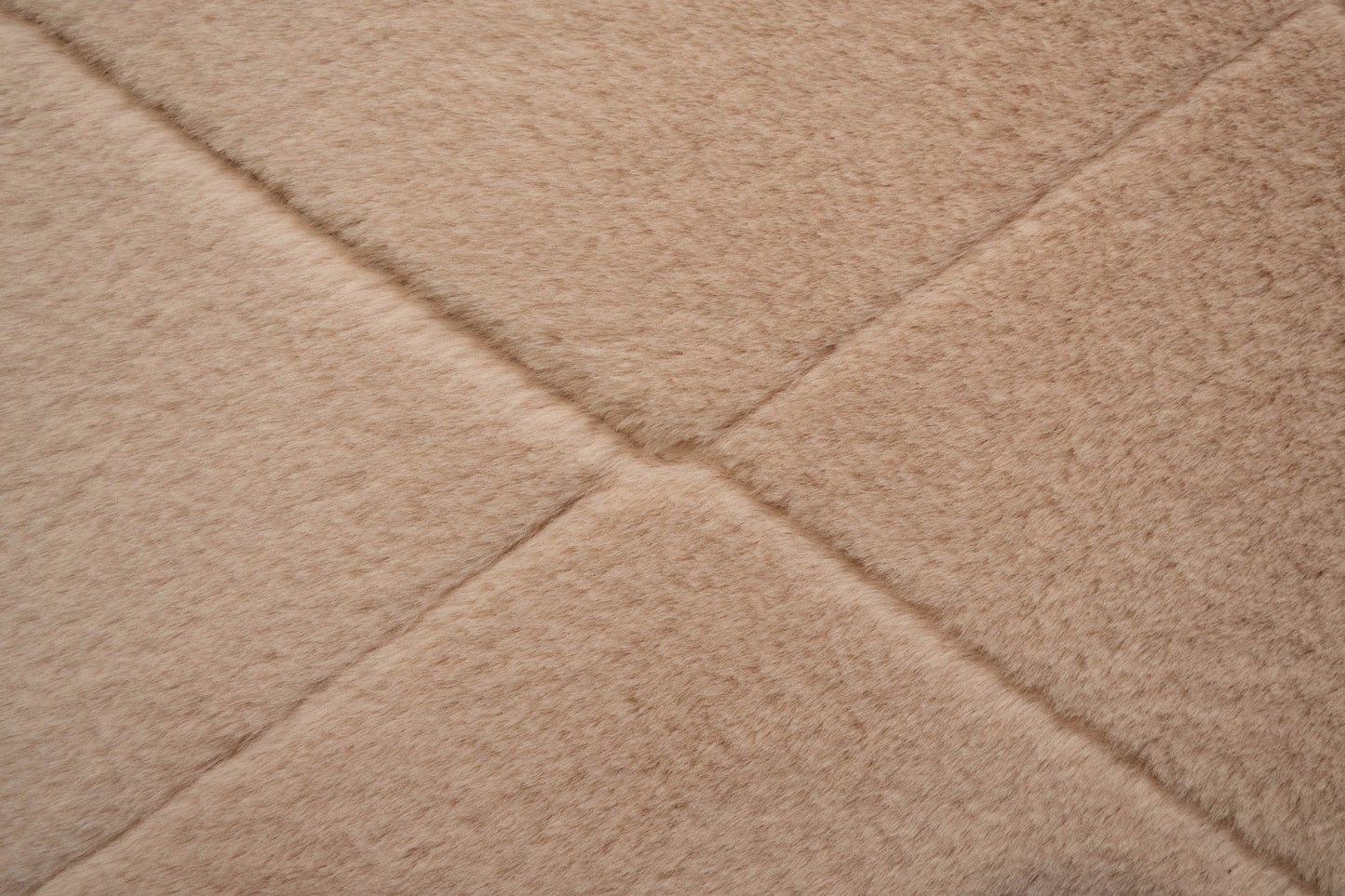 Soft pink shag rug close-up with diamond texture and stitched seam