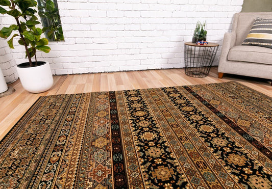 Black traditional area rug with layered geometric bands in warm gold and red tones