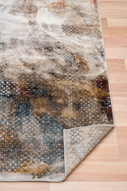 Multicolor abstract area rug with corner showing stitched edge and varied beige, blue, rust