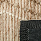 Beige wool area rug border close-up with stitched woven pattern and black backing