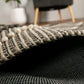 Rolled corner detail of charcoal and cream wool rug with textured weave and binding.