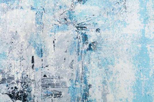Contemporary area rug close-up with mottled light blue and white abstract speckled pattern.