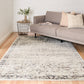 Light gray rectangular area rug with distressed abstract pattern, styled in living room