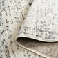 Corner detail of light gray distressed area rug showing reversed underside and binding