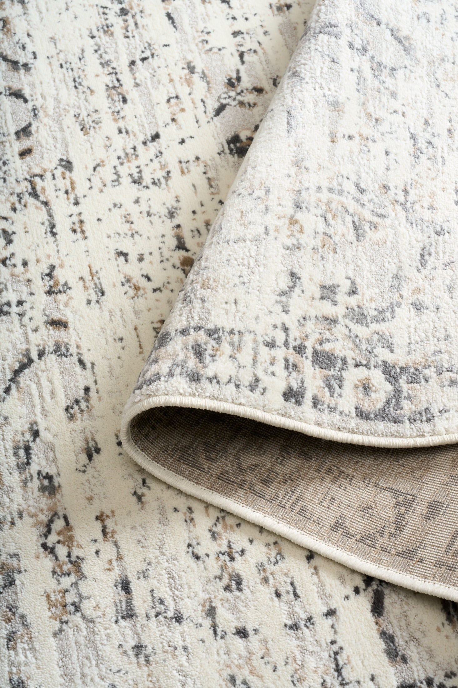 Corner detail of light gray distressed area rug showing reversed underside and binding