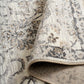 Grey and cream damask area rug with textured backing visible along rolled edge
