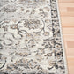 Grey and cream damask area rug with decorative border and distressed ornamental details
