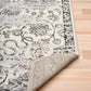 Grey and cream patterned area rug corner with short pile and tonal border