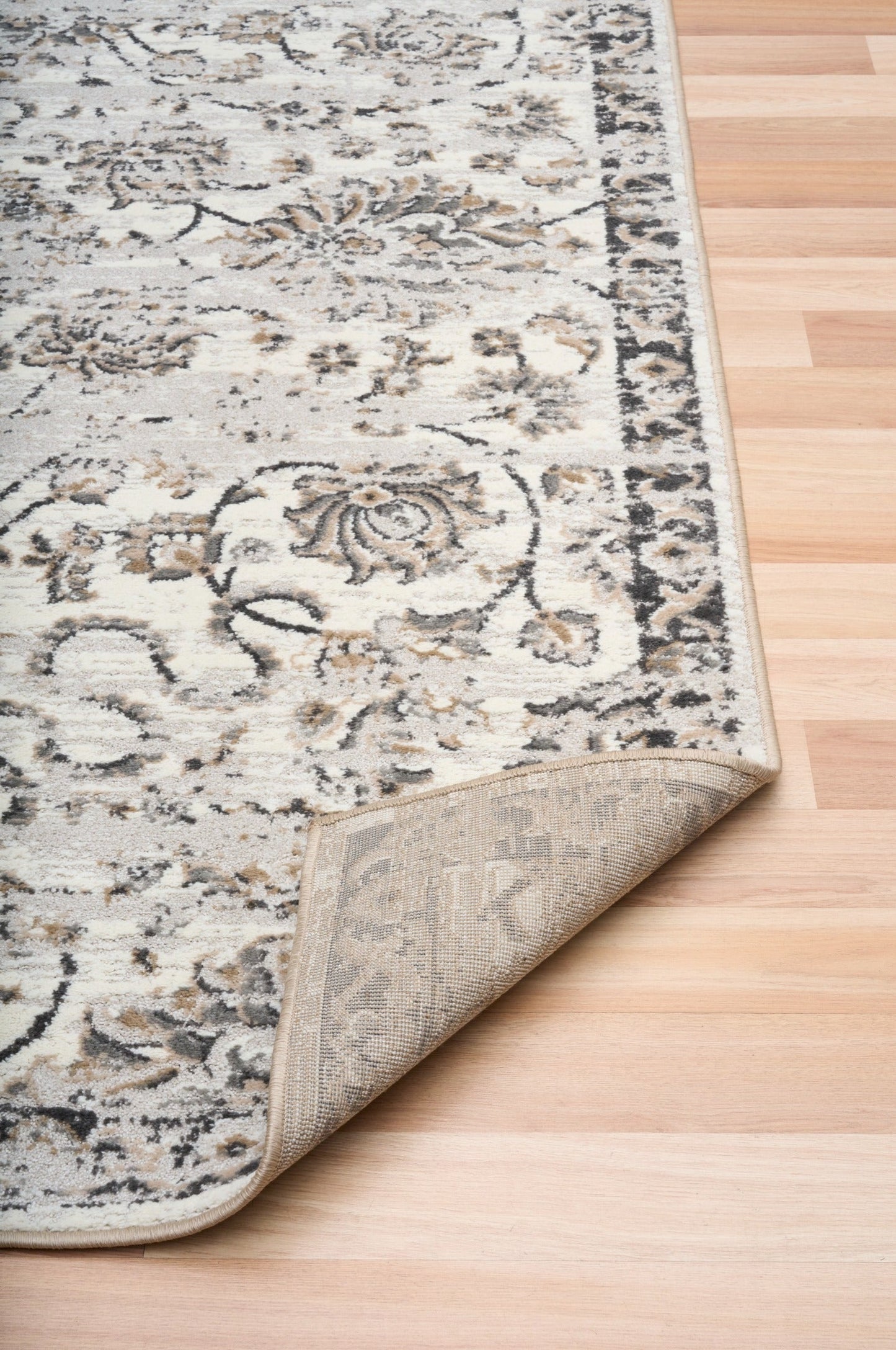 Grey and cream patterned area rug corner with short pile and tonal border