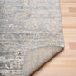 Corner of distressed light gray area rug with cream flecked pattern and short pile