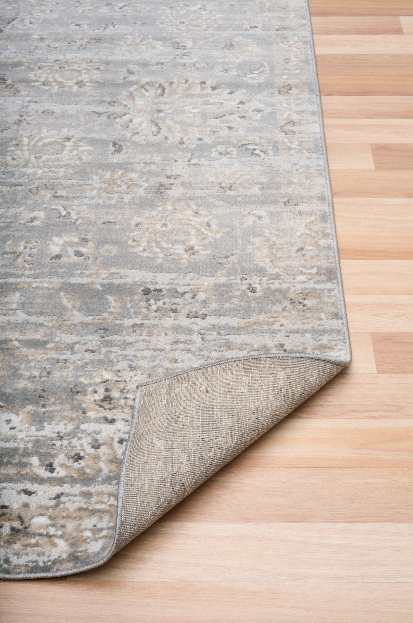 Corner of distressed light gray area rug with cream flecked pattern and short pile