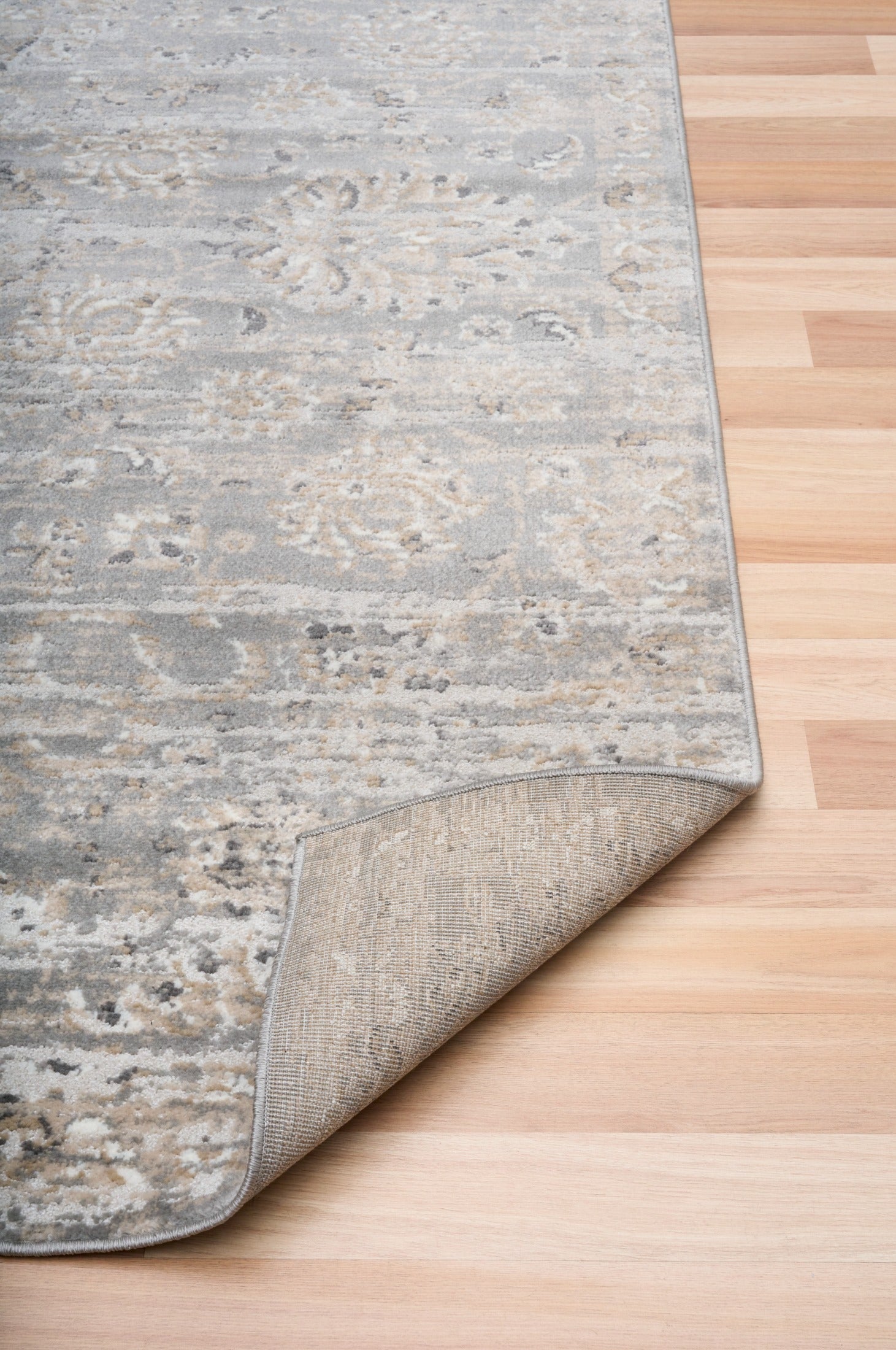 Corner of distressed light gray area rug with cream flecked pattern and short pile