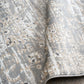 Close-up of distressed rug texture with light gray base and cream flecks