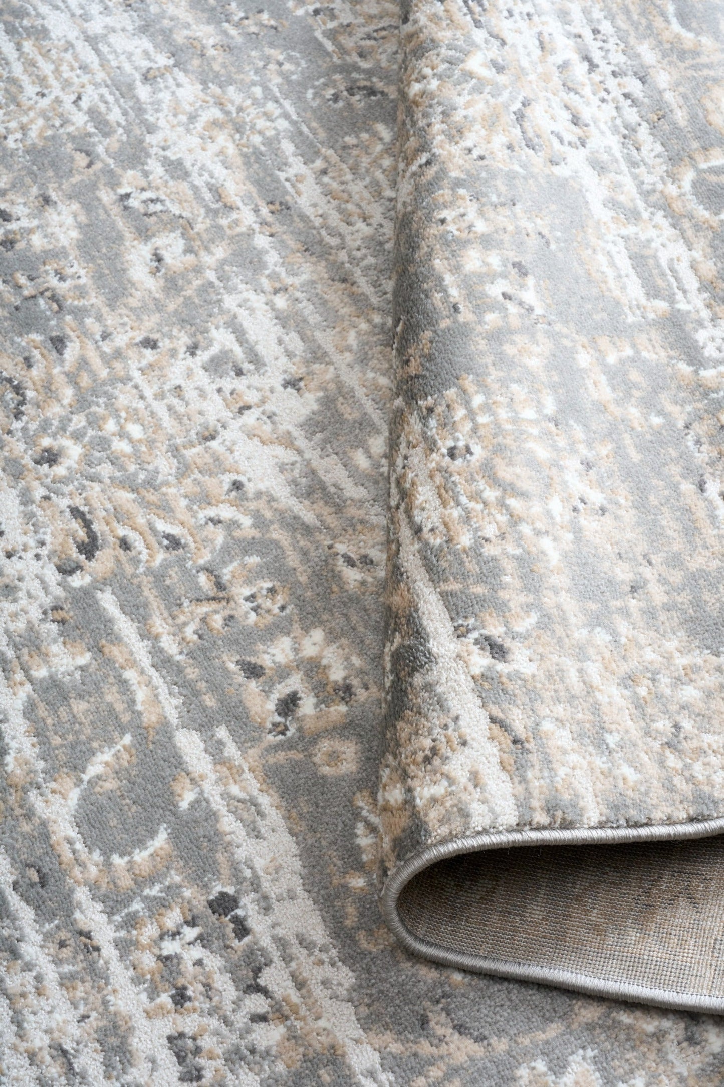 Close-up of distressed rug texture with light gray base and cream flecks