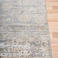 Edge of distressed light gray area rug with cream speckled pattern and short pile