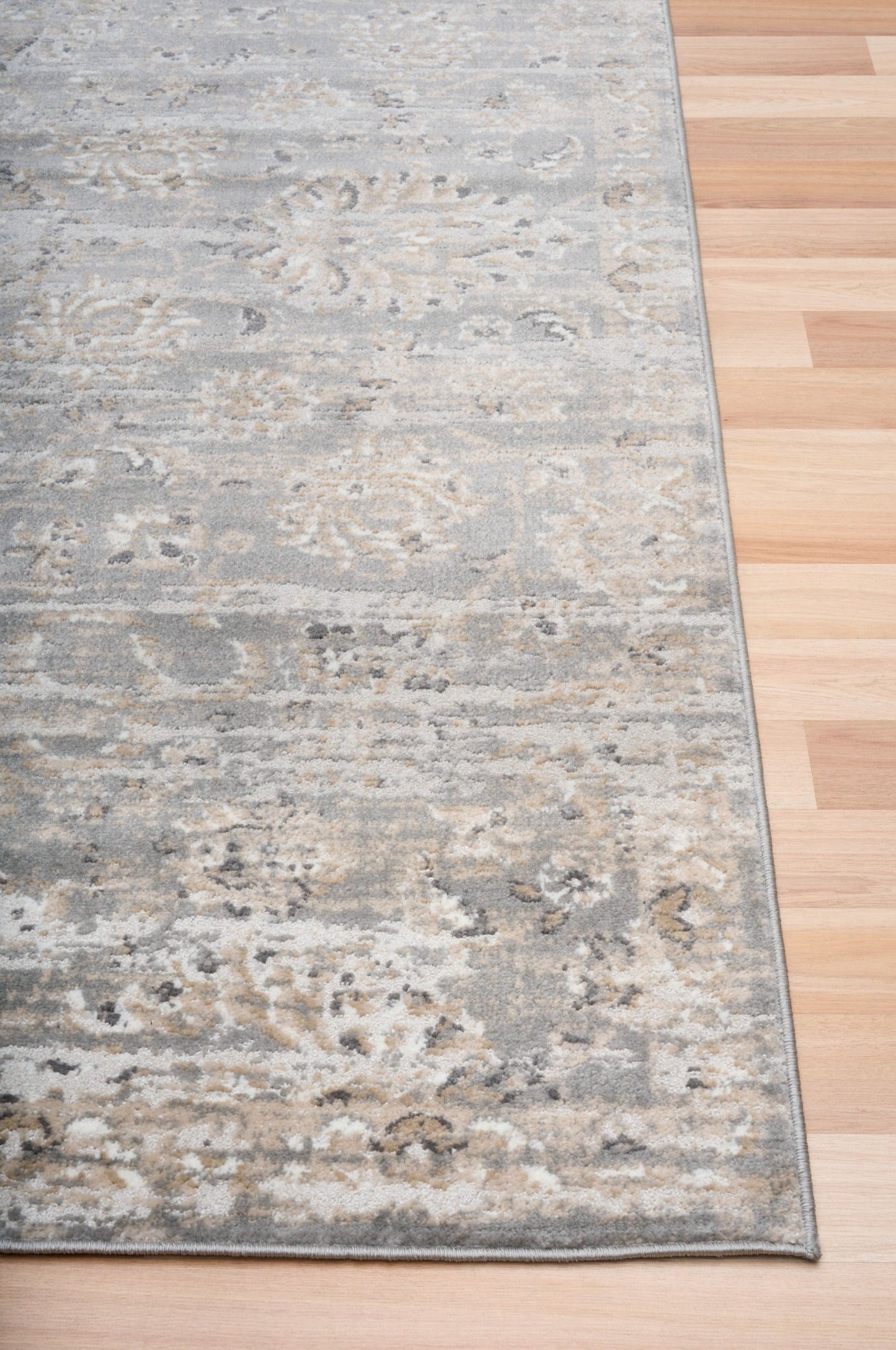 Edge of distressed light gray area rug with cream speckled pattern and short pile