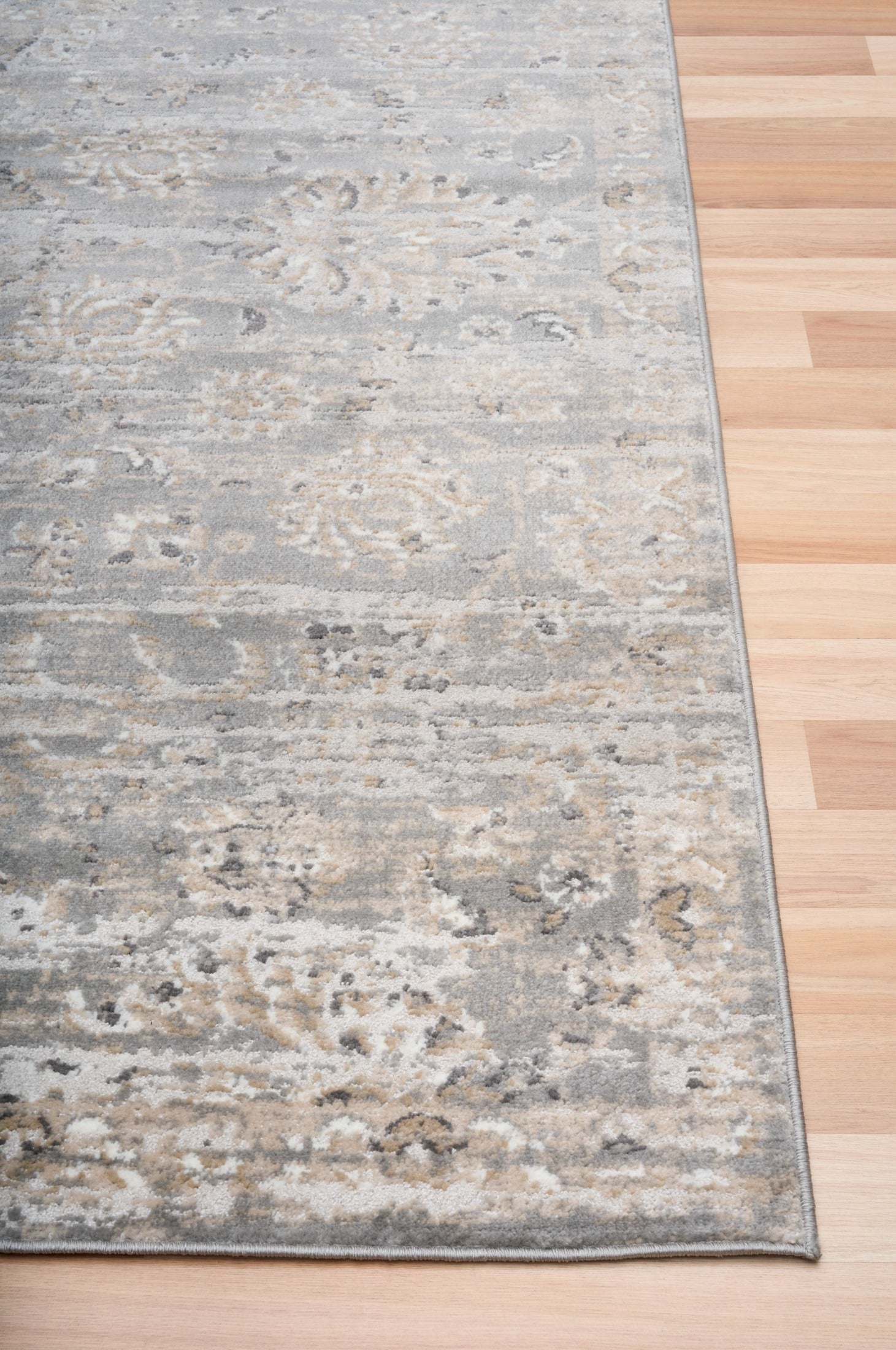 Edge of distressed light gray area rug with cream speckled pattern and short pile