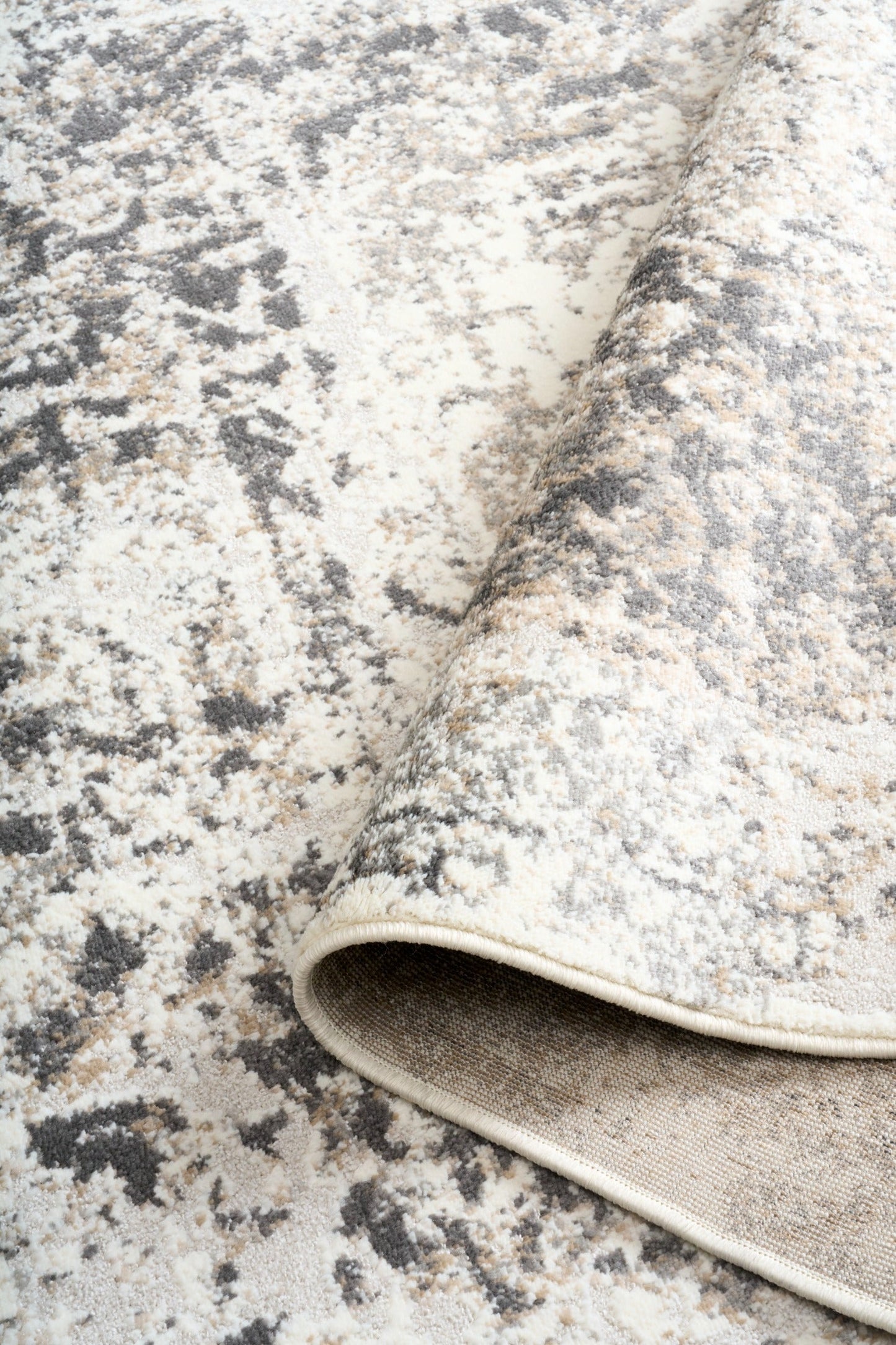 Gray and white rug pile with abstract distressed pattern and stitched edge