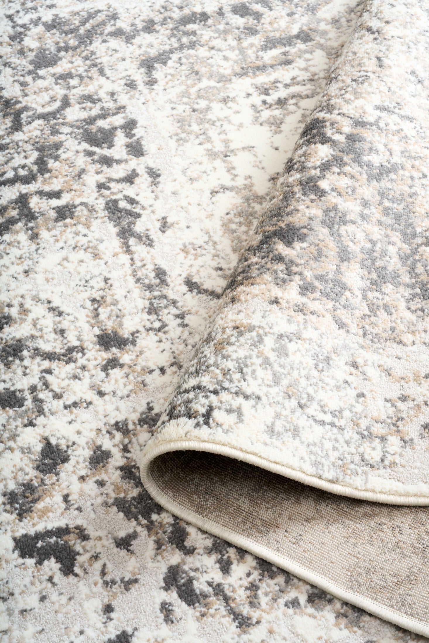 Gray and white rug pile with abstract distressed pattern and stitched edge