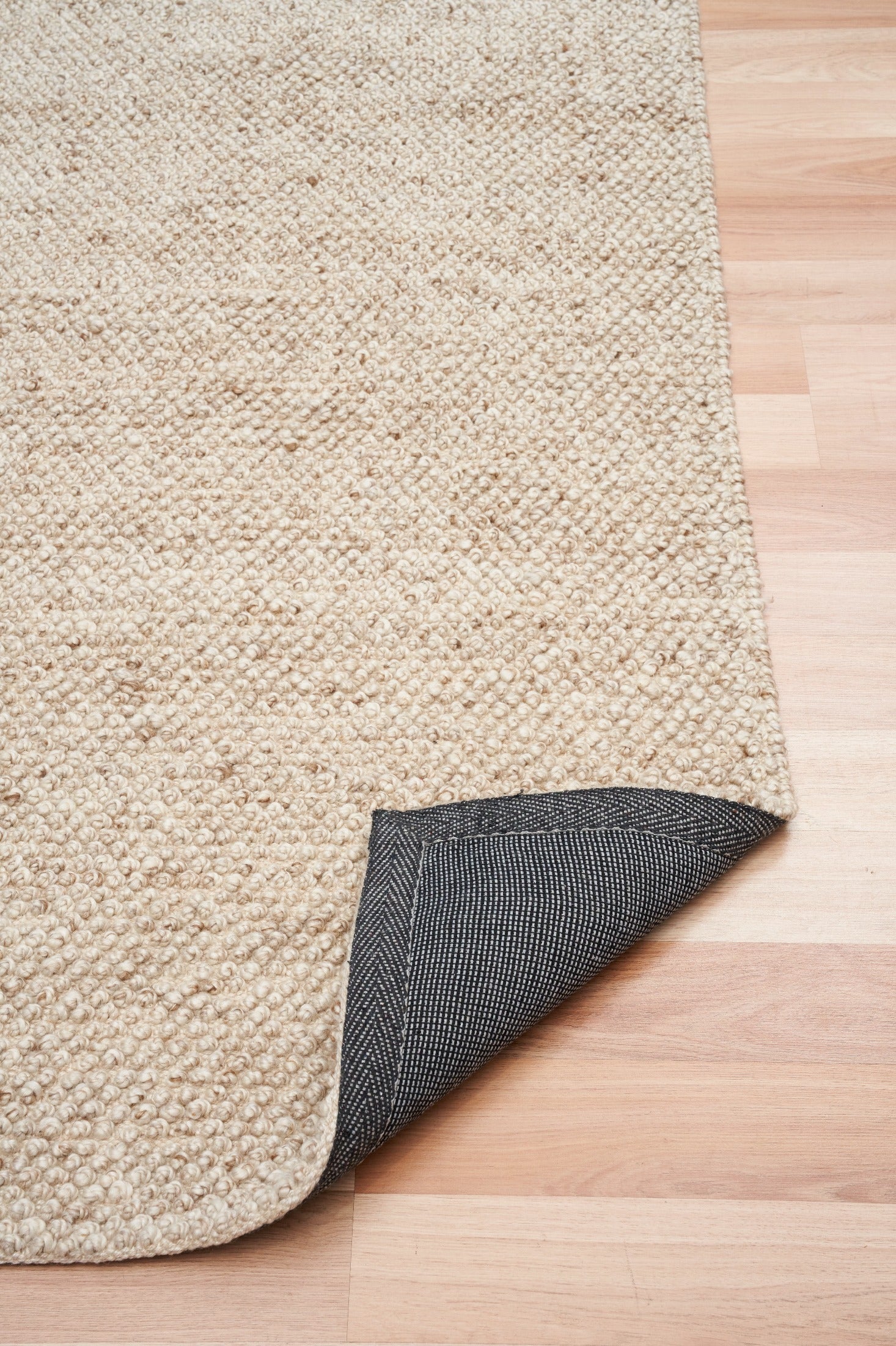 Beige woven rug corner with dark backing underside