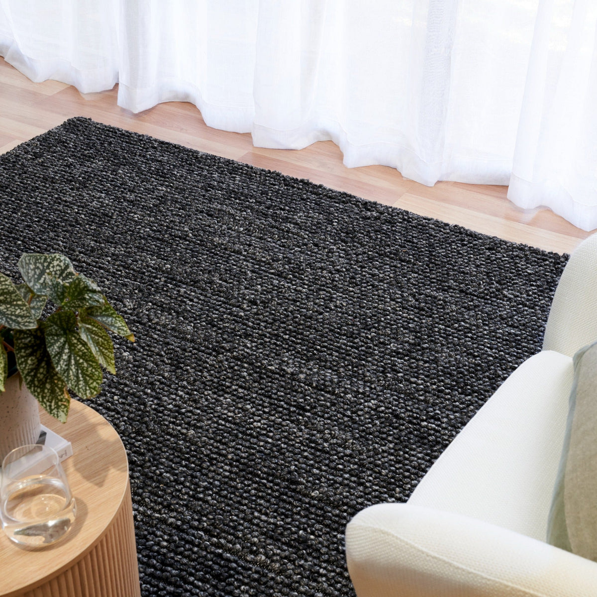 Charcoal textured area rug with tight looped weave, on a hardwood floor