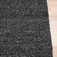 Charcoal textured rug with corner detail, shown on hardwood floor