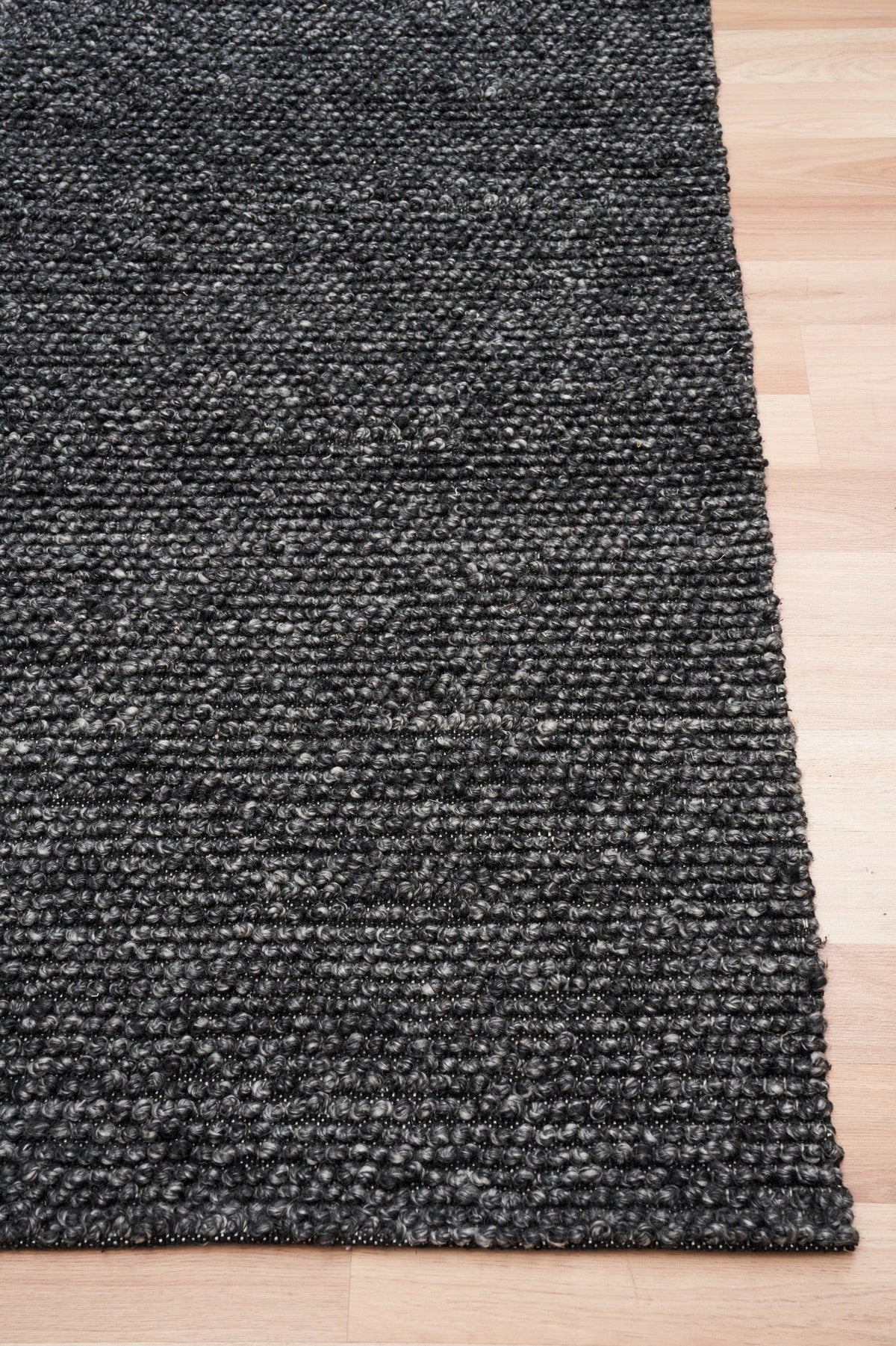 Charcoal textured rug with corner detail, shown on hardwood floor