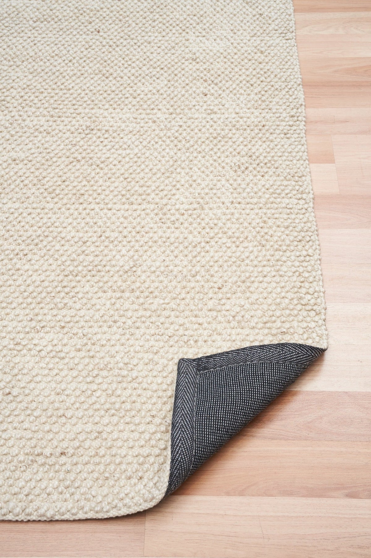 Cream rug corner with dark backing on underside