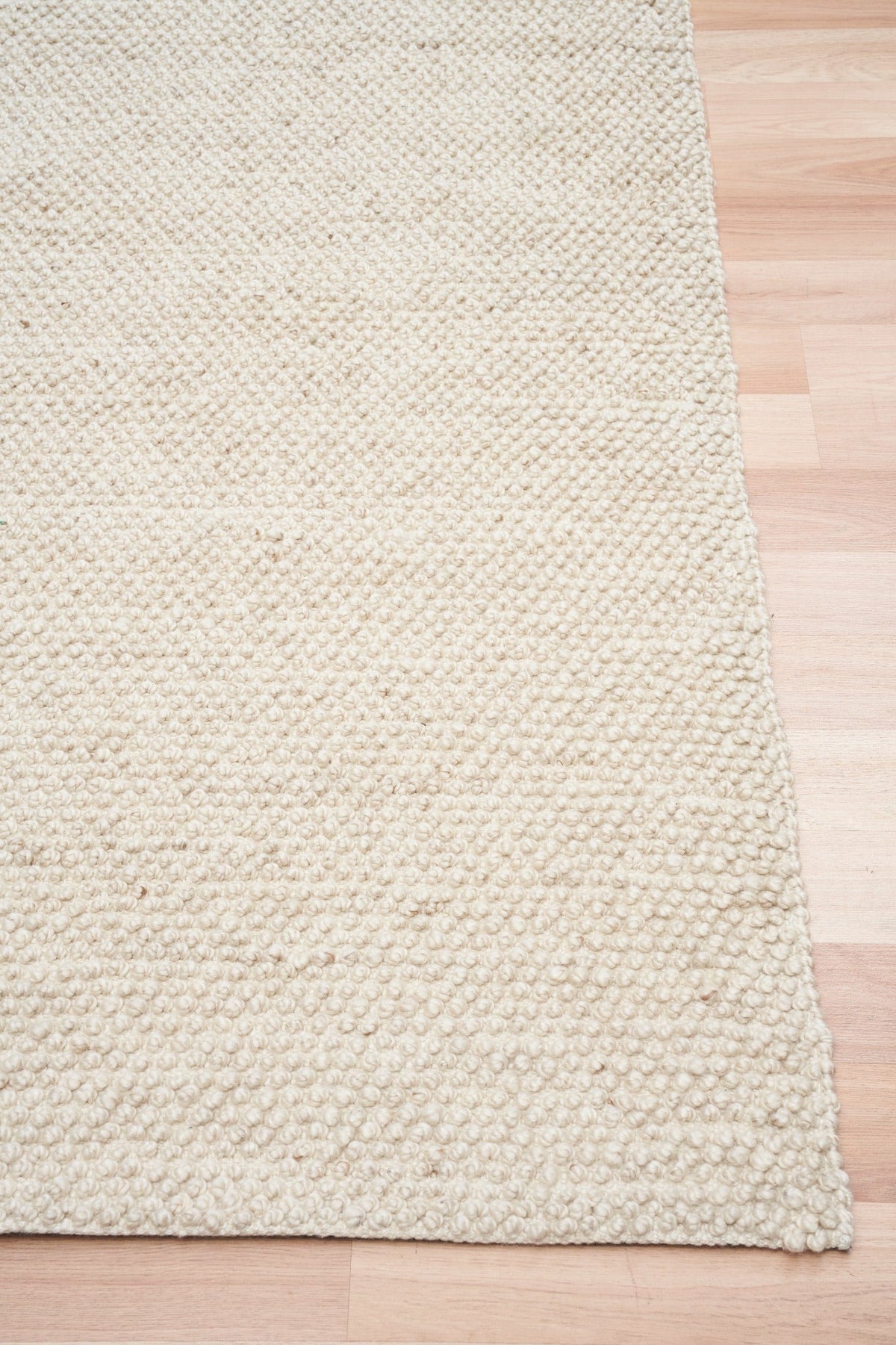 Cream woven area rug corner with textured edge